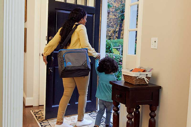 mom and toddler walking out of the house with cooler