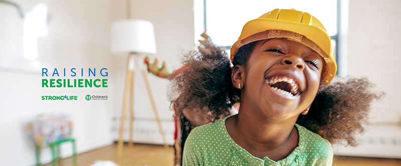 Preschooler girl laughing with raising resilience logo overlaid