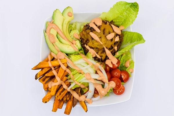 Picture of a balanced black bean burger bowl recipe with sweet potato fries, avocado and more.