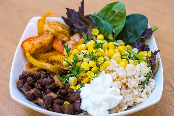 Nutritionally-balanced chicken taco bowl recipes with beans, chicken, peppers and onions, rice, avocado and more.