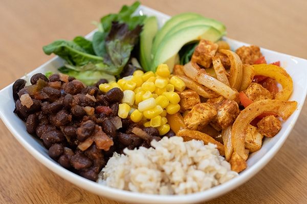 Plated vegetarian-friendly tofu taco bowl with beans, avocado, rice and more.