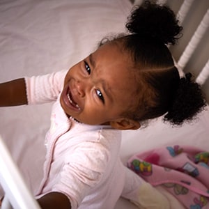 Toddler crying in her crib, fighting bedtime