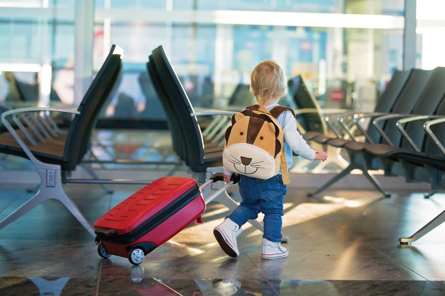 Toddler pulls their own luggage while traveling through an airport.