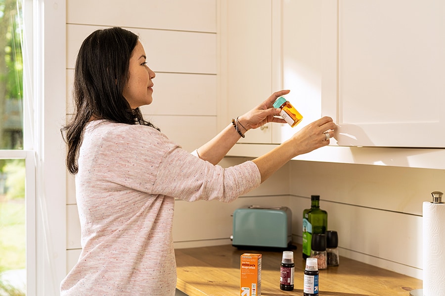 Mom putting medications (prescription and over-the-counter) away in an upper cabinet, out of a child's reach